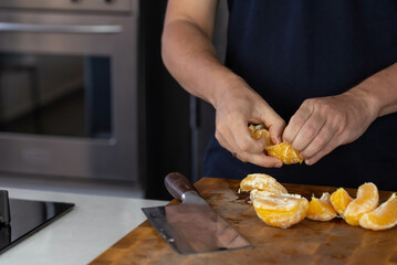 Chef cook cutting fresh orange for fruit salad on wooden cut board