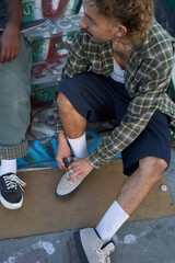 Portrait of young non-binary tying shoes at skatepark
