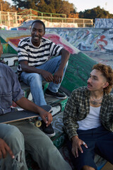 Three young skateboarders in skatepark hanging out

