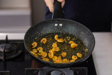 Chef cook hands roasting shrimps in wok pan with oil and spice. Seafood healthy cuisine. Flying food levitation.