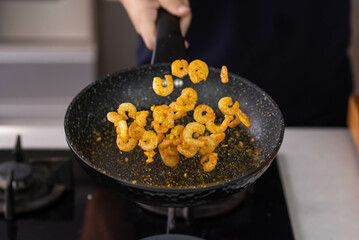 Chef cook hands roasting shrimps in wok pan with oil and spice. Seafood healthy cuisine. Flying food levitation.