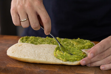 Chef cook hands making fresh diet avocado toast on bread with fork. Vegetarian and vegan cuisine. Healthy vitamin breakfast.
