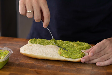 Chef cook hands making fresh diet avocado toast on bread with fork. Vegetarian and vegan cuisine. Healthy vitamin breakfast.