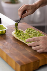 Chef cook hands making fresh diet avocado toast on bread with fork. Vegetarian and vegan cuisine. Healthy vitamin breakfast.