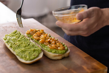 Chef cook hands making fresh diet avocado toast with seafood shrimps. Healthy vitamin breakfast.