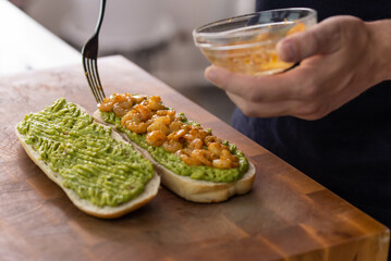 Chef cook hands making fresh diet avocado toast with seafood shrimps. Healthy vitamin breakfast.