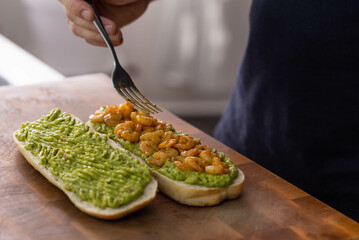 Chef cook hands making fresh diet avocado toast with seafood shrimps. Healthy vitamin breakfast.