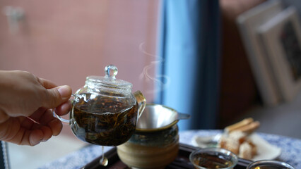 Traditional tea set tray with modern transparent pot and clear small cup in cozy Chinese room. Natural healthy hot clear drink with dried leaves give good aroma and relax for drink.