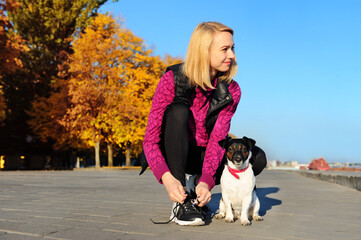 Woman tying shoelaces while jogging with her dog