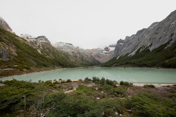 Naklejka na ściany i meble Panorama view of glacier water Emerald Lake i9n the mountaintop, in Ushuaia, Tierra del Fuego Patagonia Argentina. Turquoise color water lake surrounded by the Andes mountains and forest.