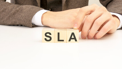 hand holding wooden cube blocks with text sla - service level agreement - on white table background. financial, marketing and business concepts