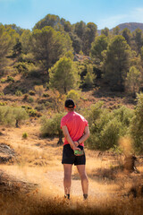 Man in cap and red t-shirt admiring the natural landscape.