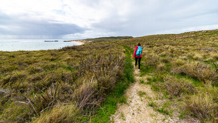 Fototapeta premium hiker girl with a backpack walks along paradise bay on rottnest island, near perth in western australia, paradise beaches of western australia