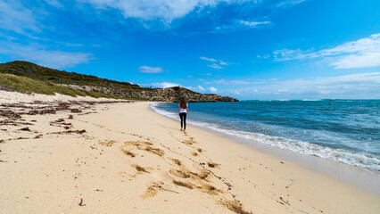 hiker girl with a backpack walks along paradise bay on rottnest island, near perth in western...