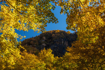 Fototapeta premium View through a frame of leaves towards the rocky summit of Smugglers Notch in the fall near Stowe, Vermont