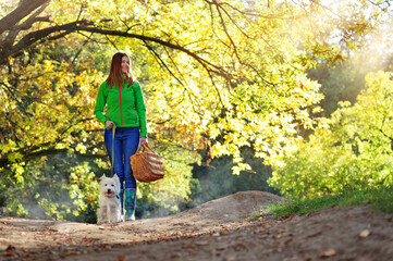 Woman in green jacket walking with her puppy in the forest