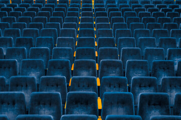 Rows of dark blue seats in empty assembly hall for performance. Front view.