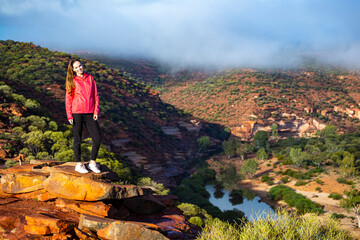 long-haired girl walks along a ridge on the red rocks of kalbarri national park in western australia; hiking in the wilderness, australian outback