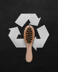 Circular recycling symbol with wooden hair brush on black background. Eco concept