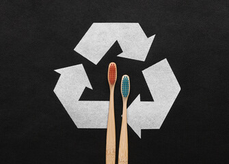 Circular recycling symbol with wooden toothbrushes on black background. Eco concept