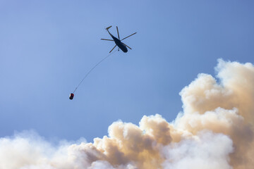 Wildfire Service Helicopter flying over BC Forest Fire and Smoke on the mountain near Hope during a hot sunny summer day. British Columbia, Canada. Natural Disaster