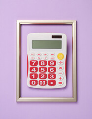 Calculator in a golden frame on a pastel background. Business concept. Top view