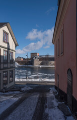 Winter view in Stockholm archipelago town Vaxholm, icy lake, snow, pier and residential houses a sunny day