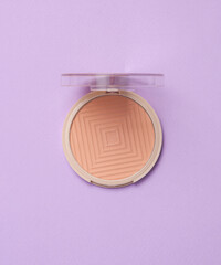 Powder box on a purple pastel background. Top view