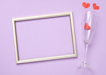 Champagne glasses with hearts and golden frame on pastel background. Romantic, love concept. Top view