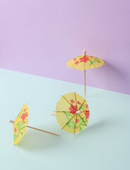 Creative summer layout with cocktail umbrellas on pastel background. Conceptual pop. Minimal still life