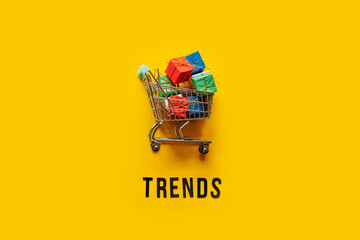 Ecommerce Retail Shopping trends concept. Word Trends and mini shopping cart with box on yellow...