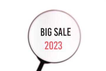 Phrase Big Sale 2023 through a magnifying glass on a white screen background. Shopping concept