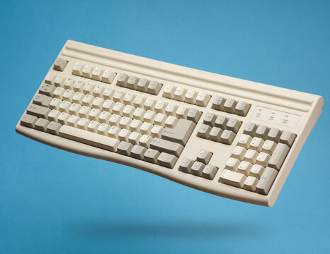 Old fashioned retro 80s keyboard levitating on blue background with shadow