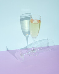 Creative layout with champagne glass on two tone pastel background. Visual trend. Minimalistic aesthetic still life. Romantic date, holiday