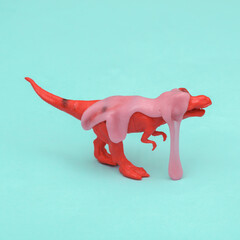Creative layout, toy tyrannosaurus with slime on blue background. Visual trend. Fresh idea. Concept...