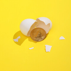 Creative layout with hatched bitcoin from an egg. Bright yellow background with shadow. Business concept. Visual trend. Minimalistic aesthetic still life. Fresh idea