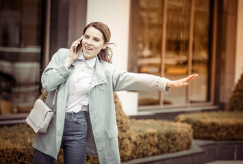 Fototapeta premium Cute lady catches car in city and talks on the phone