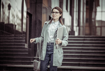 Obraz premium Pretty business woman comes down the steps with laptop. Lifestyle