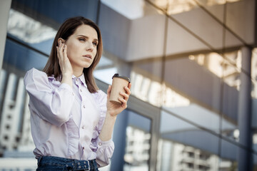 Cute business woman talking on wireless headphones on the background of the business center