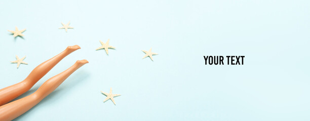 Doll female bare feet on blue background with sea stars. Summer rest, Sunbathe the beach. Creative minimalistic layout. Copy space