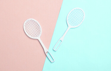 Doll tennis rackets on a blue-pink pastel background. Top view