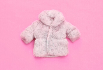 Fototapeta na wymiar Doll fur coat on pink background. Minimalism fashion layout. Top view. Flat lay