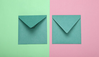 Craft envelopes on green-pink pastel background. Top view