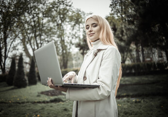 Young stylish woman holding laptop in the park