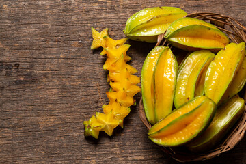 Organic carambola Asian fruit whole in a wicker basket and cut, star fruit, grown on an organic farm on a rustic wooden table top, top view with space for writing