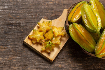 organic carambola asian fruit, star fruit, grown on organic farm in a wicker basket on a rustic wooden table top view with space for writing