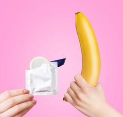 Yellow banana and female hand holding a package with a condom.