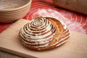  Artisan Sourdough bread baked at home.  Beautiful crust of the bread. Cane banneton at the background