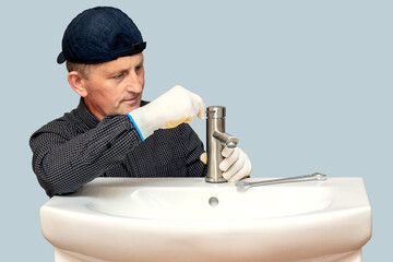 The master plumber screws the faucet to the sink in the bathroom