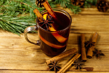Christmas mulled wine with spices and fir tree branches and cones on wooden table